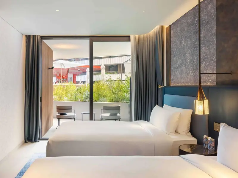 Chambre lumineuse avec un grand lit et une vue sur une terrasse.