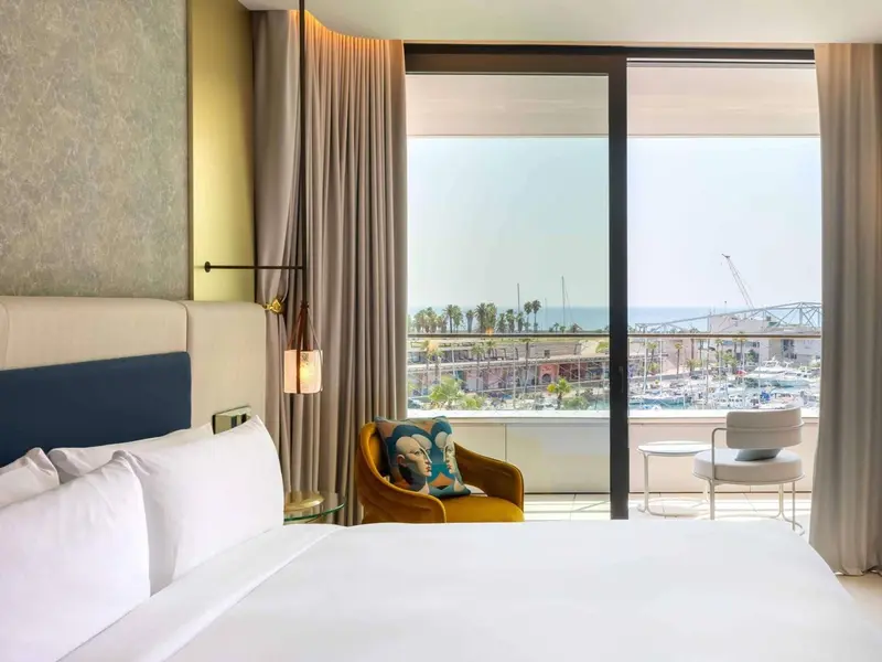 Une chambre lumineuse avec un lit blanc et une vue sur la mer.