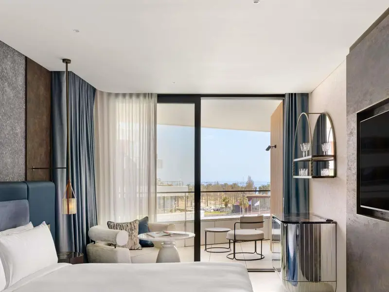 Chambre lumineuse avec un grand lit et une vue sur la mer.