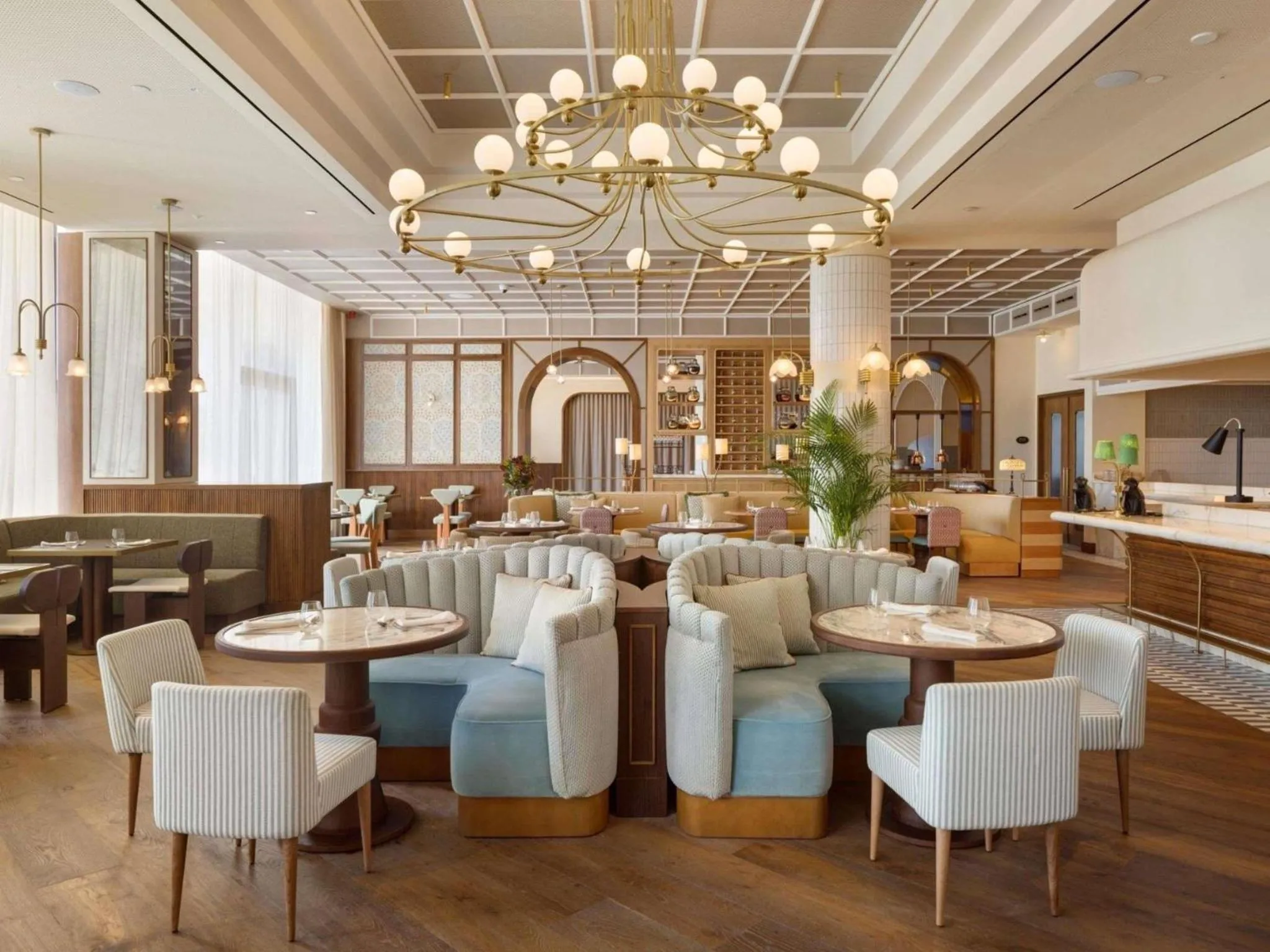 Une salle de restaurant lumineuse avec des tables rondes et des banquettes confortables.