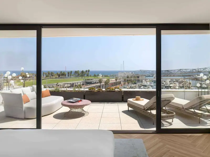 Un salon lumineux s'ouvre sur une terrasse avec vue sur la mer et un port de plaisance.