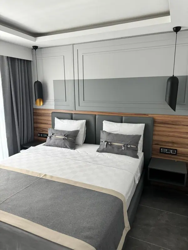 Une chambre moderne avec un grand lit recouvert d'une couette blanche et de coussins gris.