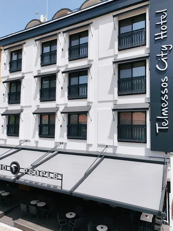 Façade d'un bâtiment blanc avec des balcons et une marquise au-dessus d'une terrasse.