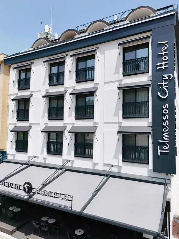 Façade d'un bâtiment blanc avec des balcons et une marquise au premier plan.