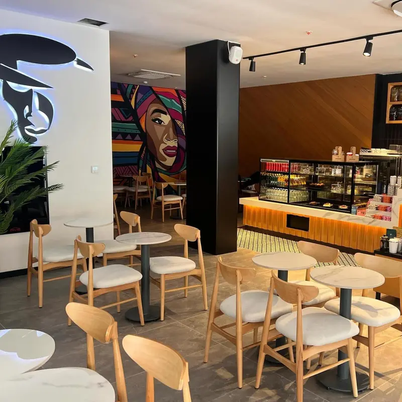 Une salle lumineuse avec des tables et des chaises en bois, décorée de peintures murales colorées.