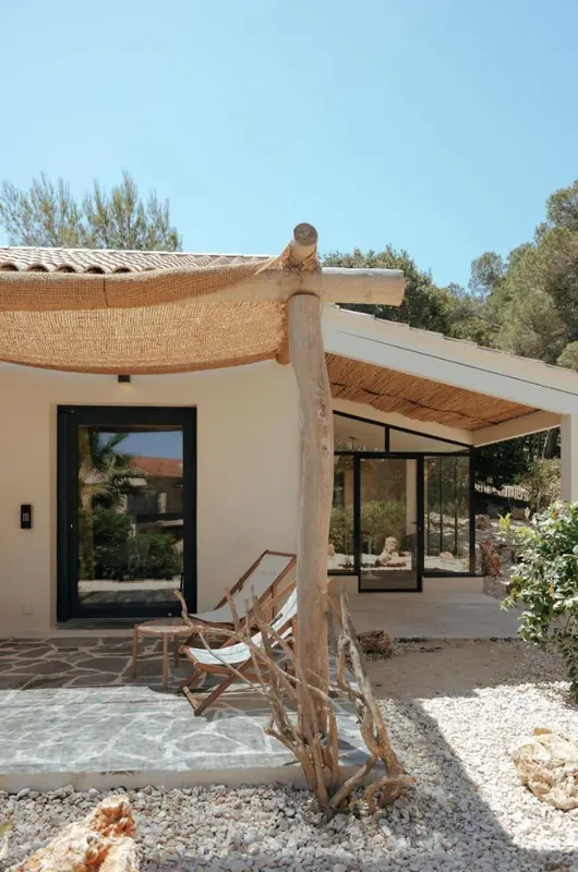 Terrasse ombragée devant une entrée de logement.