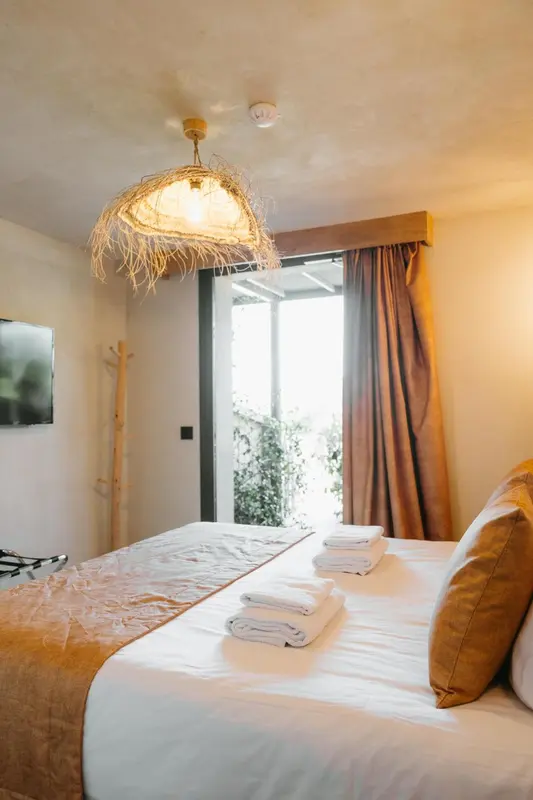 Une chambre lumineuse avec un grand lit et un accès à une terrasse.