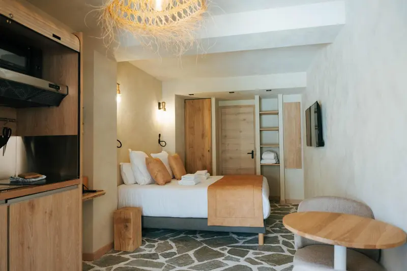 Une chambre lumineuse avec un lit fait et un coin repas.