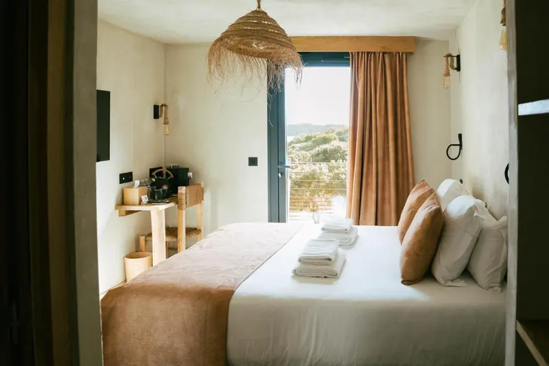Une chambre lumineuse avec un grand lit et vue sur un paysage montagneux.