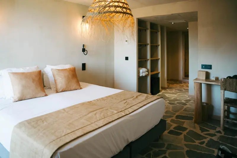 Une chambre lumineuse avec un grand lit et un bureau en bois.