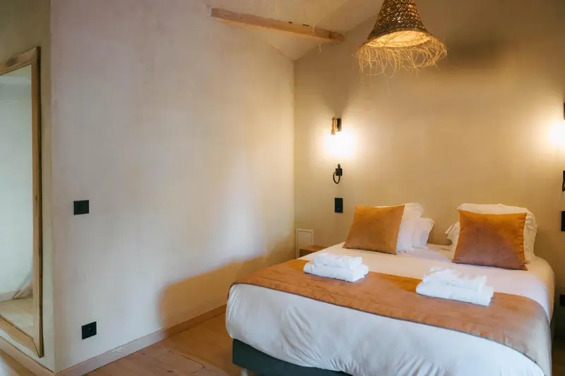 Une chambre lumineuse avec un lit recouvert d'oreillers et de couvertures.