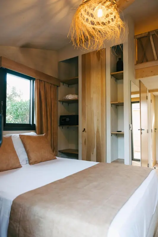 Une chambre lumineuse avec un lit recouvert d'une courtepointe et des rangements en bois.