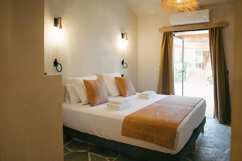 Une chambre lumineuse avec un grand lit et un accès à une terrasse.