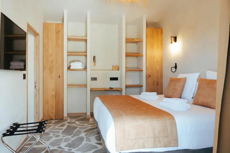 Une chambre lumineuse avec un lit recouvert d'une courtepointe et des meubles en bois.