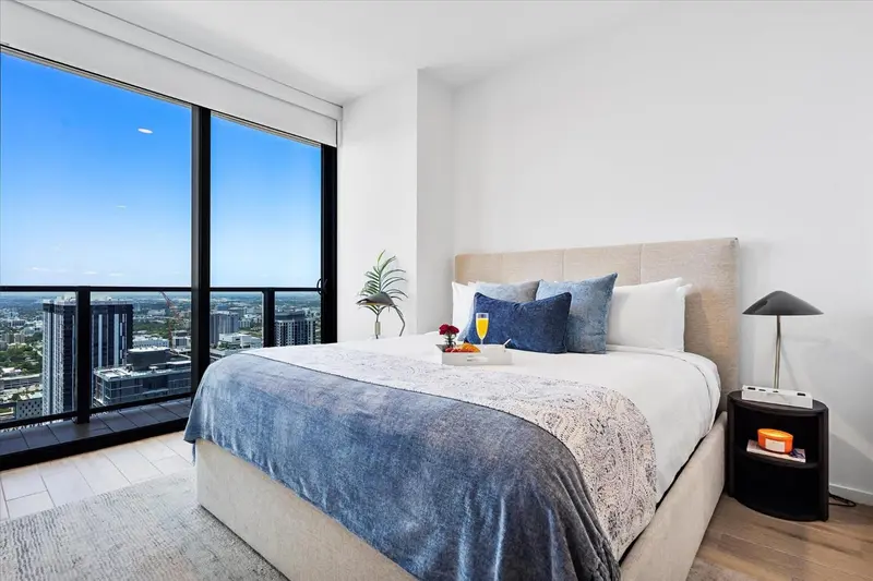 Une chambre lumineuse avec un grand lit et une vue sur la ville.