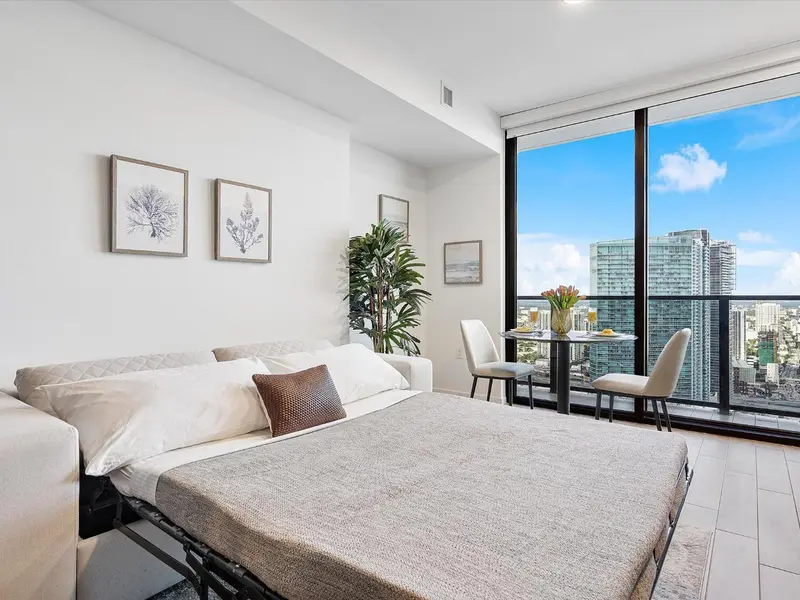 Une chambre lumineuse avec un grand lit et un coin repas près d'une fenêtre.