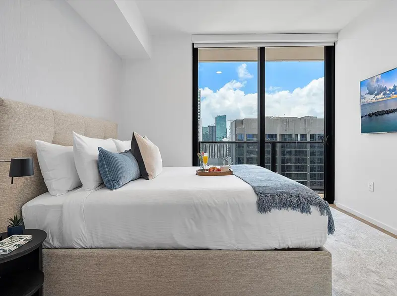 Une chambre lumineuse avec un grand lit et une vue sur la ville.