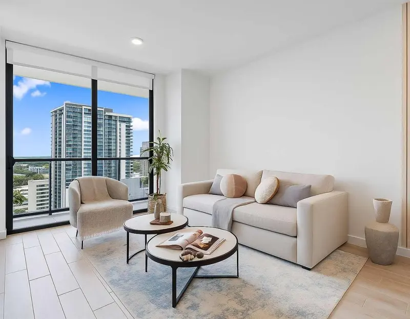 Un salon moderne avec canapé, fauteuils et tables basses devant une grande baie vitrée.
