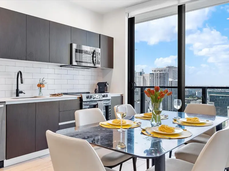 Une cuisine moderne s'ouvre sur une table à manger avec vue sur la ville.