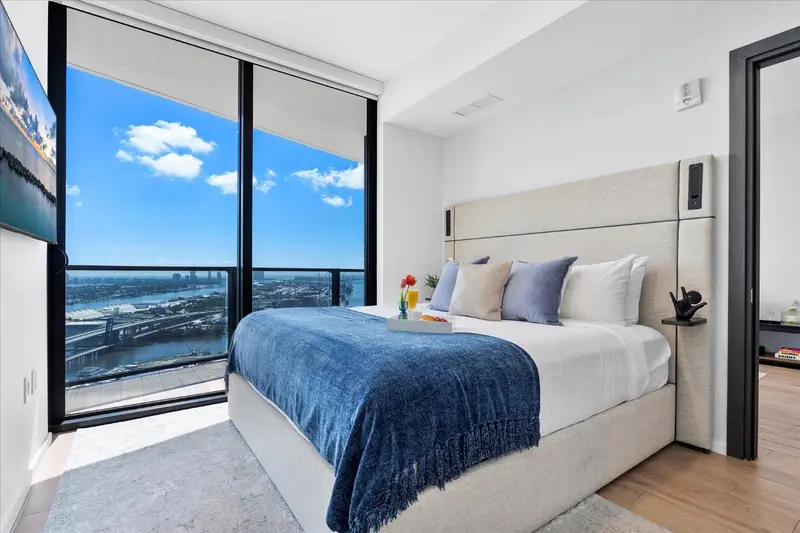 Chambre moderne avec un grand lit et une vue panoramique sur la ville.