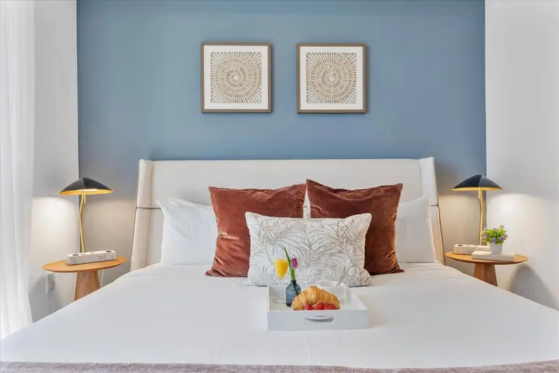 Un lit recouvert de coussins et d'une couverture blanche, avec un plateau de petit-déjeuner posé dessus.