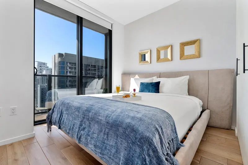 Une chambre lumineuse avec un grand lit et une vue sur la ville.