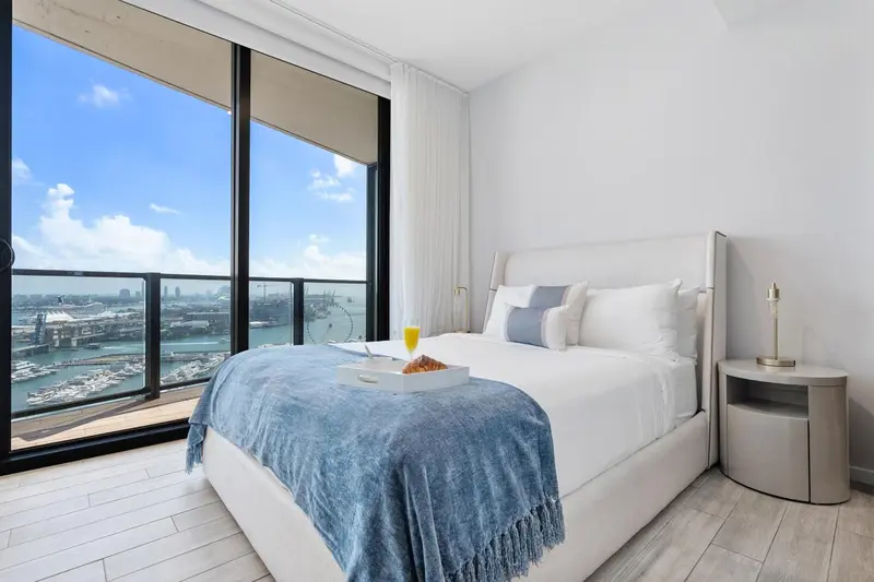 Une chambre lumineuse avec un grand lit et une vue sur la ville.