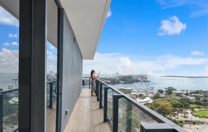 Une personne se tient sur un balcon avec vue sur la mer et la ville.