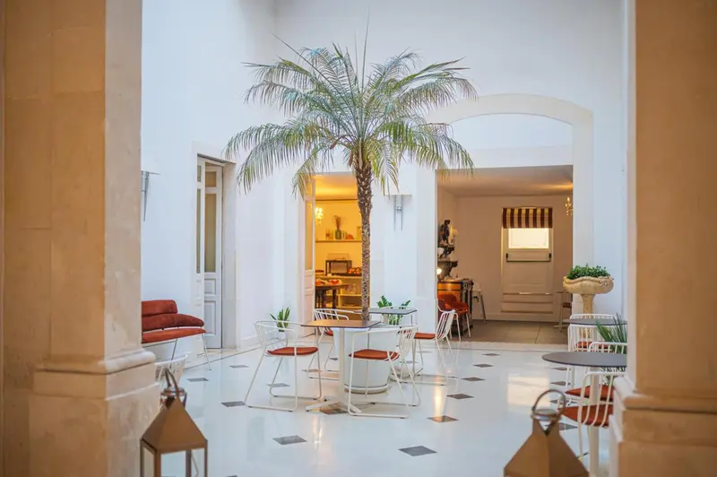 Un espace intérieur lumineux avec des tables et des chaises autour d'un palmier.