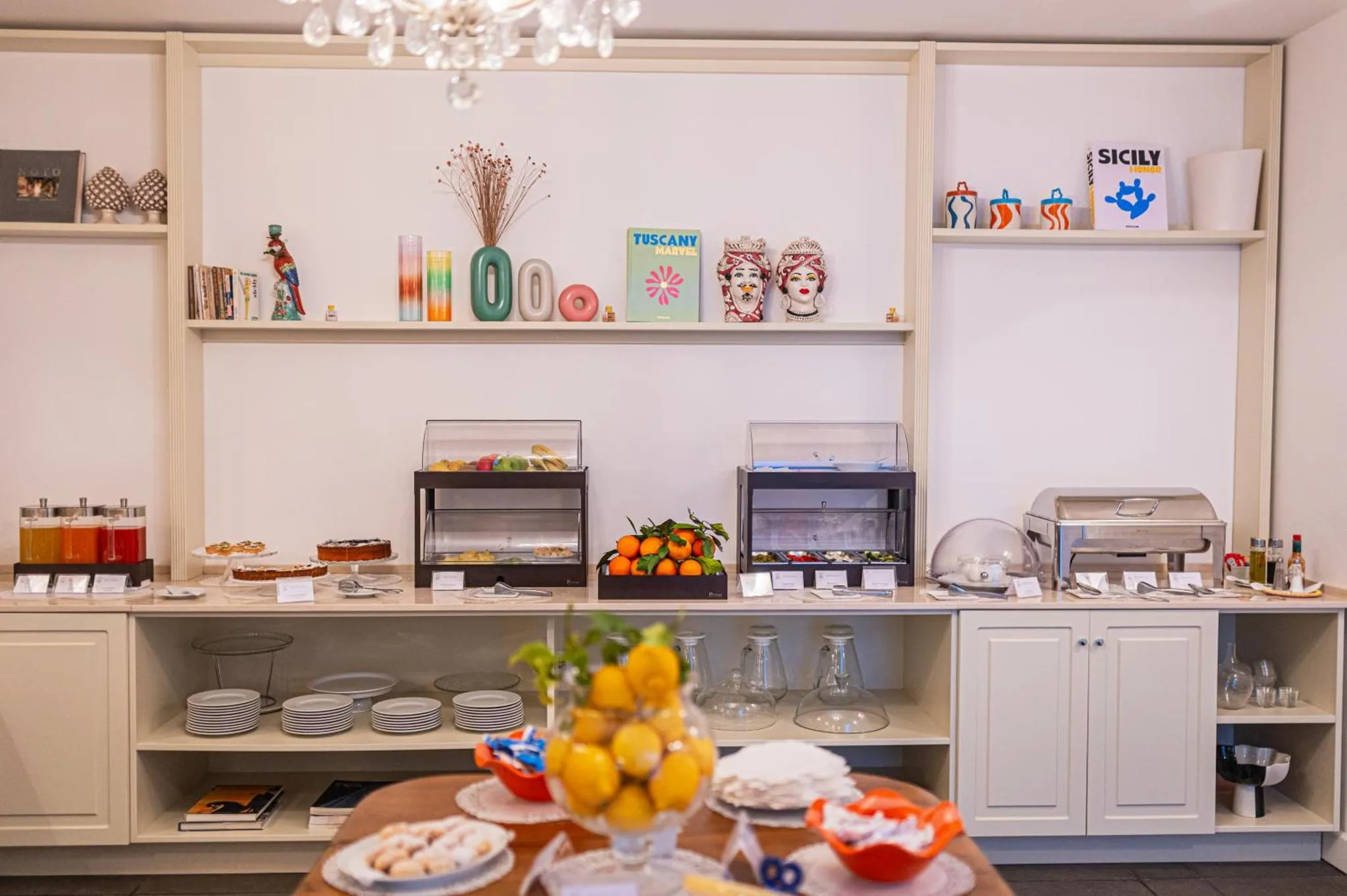 Un buffet propose des pâtisseries, des fruits et des boissons dans une salle lumineuse.