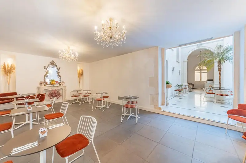 Une salle lumineuse avec des tables et des chaises, donnant sur une cour intérieure.
