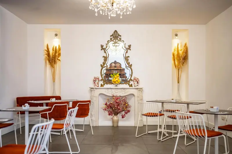 Une salle lumineuse avec des tables et des chaises, décorée d'un miroir et de plantes.