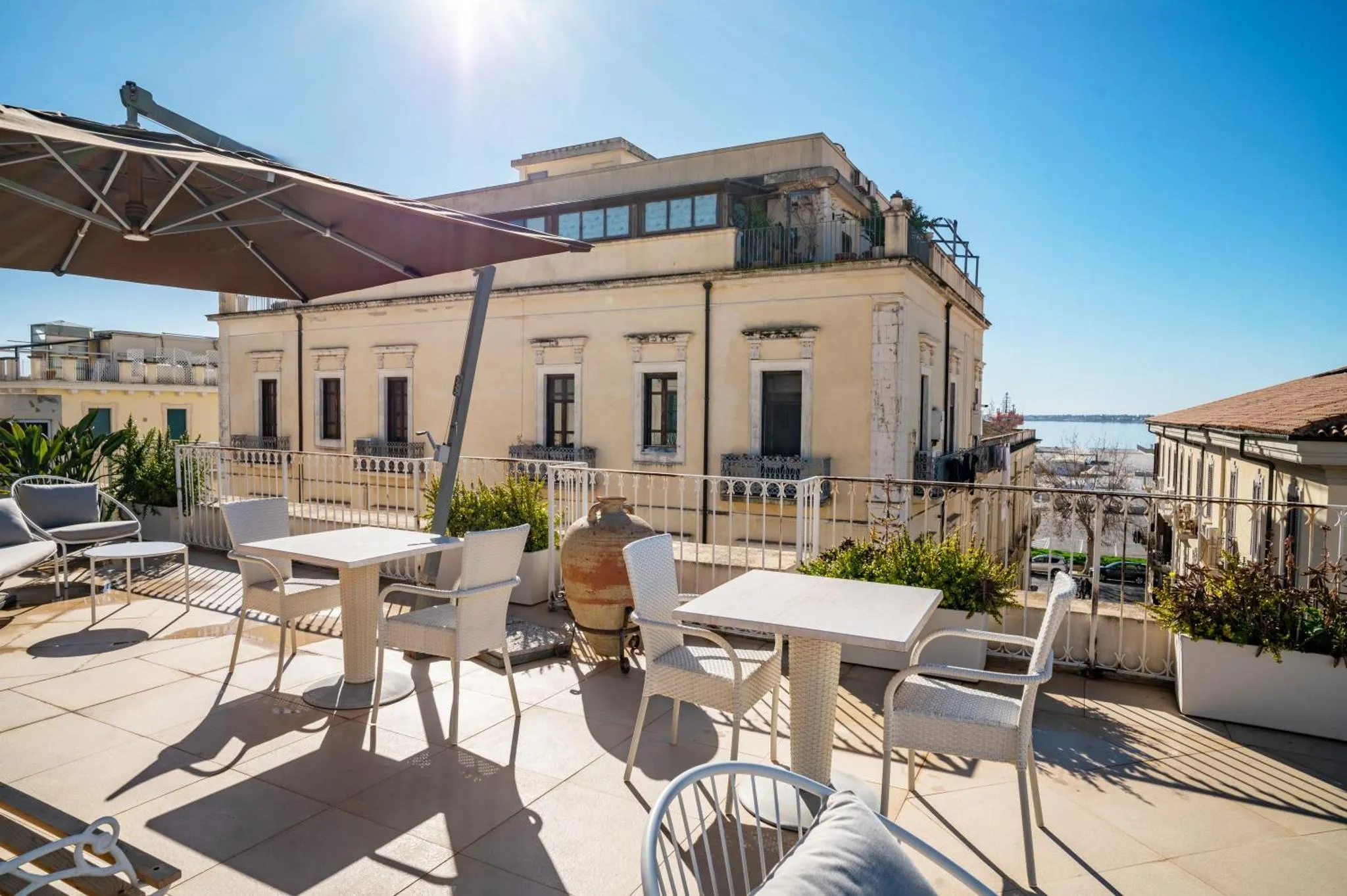 Terrasse aménagée avec tables et chaises offrant une vue sur la mer.