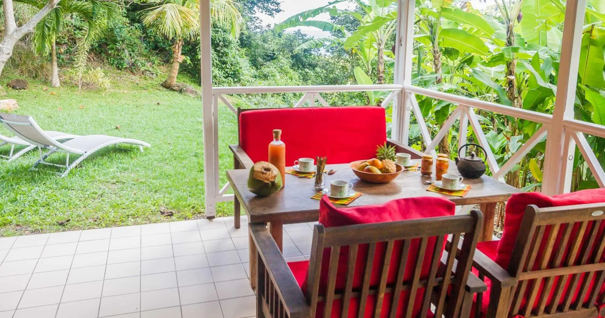 Une table de repas est dressée sur une terrasse ombragée.