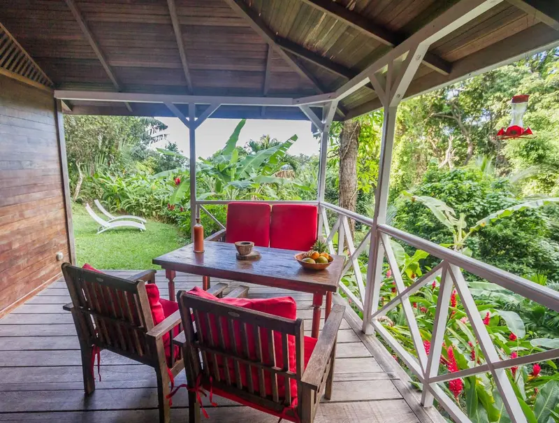 Une table et des chaises en bois sont disposées sur une terrasse couverte.