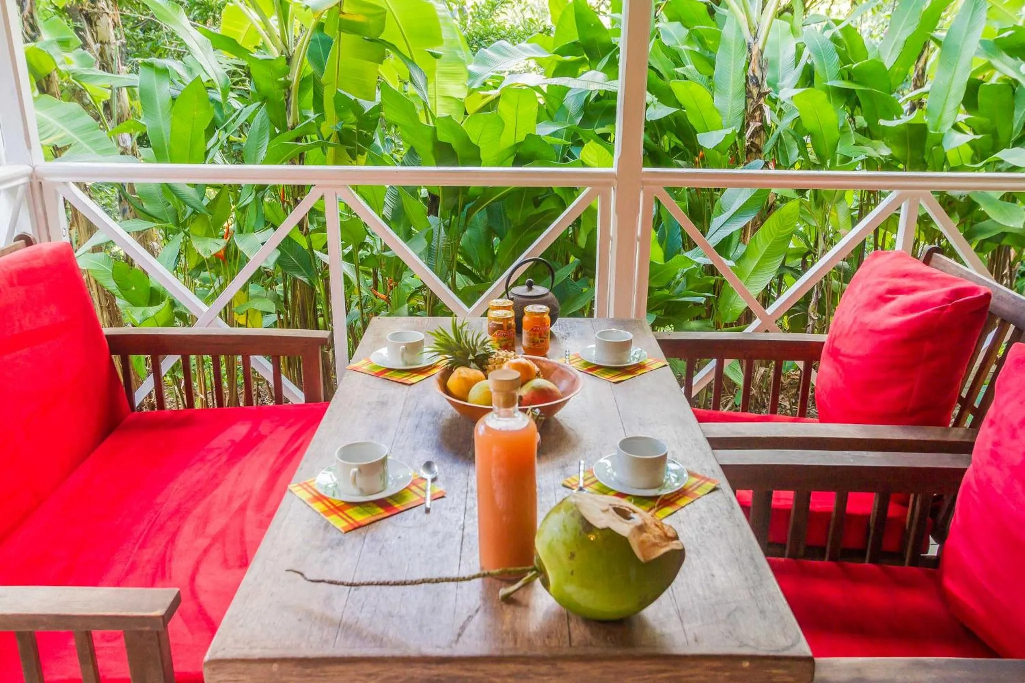 Une table de repas est dressée sur une terrasse ombragée.