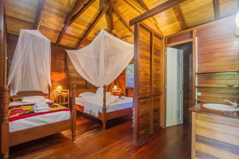 Deux lits simples avec moustiquaires dans une chambre en bois.