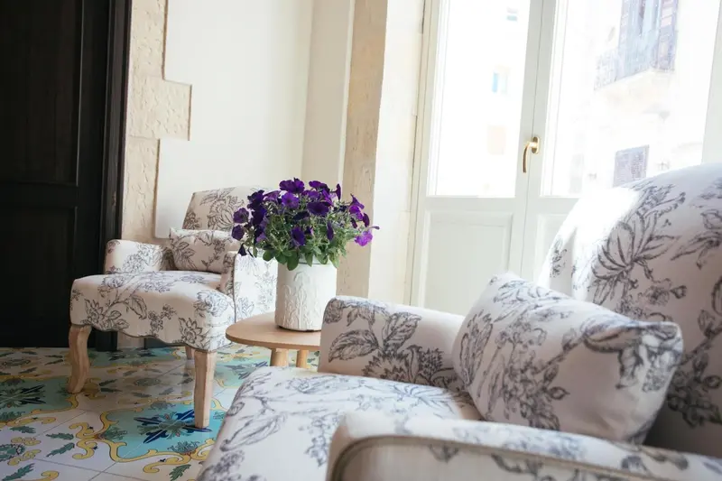 Deux fauteuils fleuris sont disposés de part et d'autre d'une petite table avec un bouquet de fleurs.