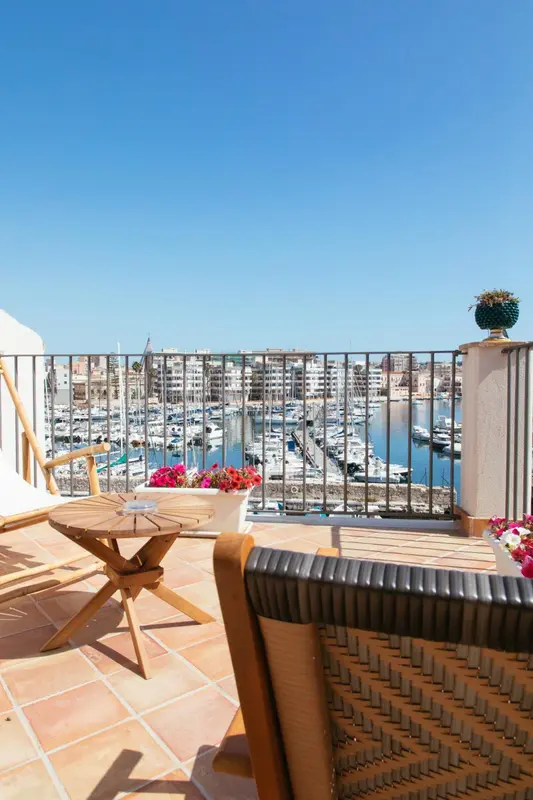 Terrasse ensoleillée avec vue sur un port de plaisance et la ville.