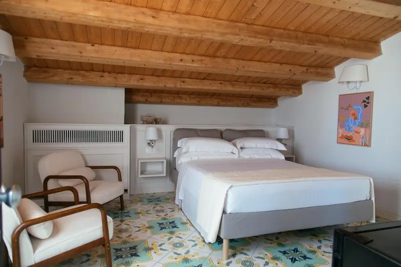 Une chambre lumineuse avec un lit blanc et des éléments décoratifs colorés.