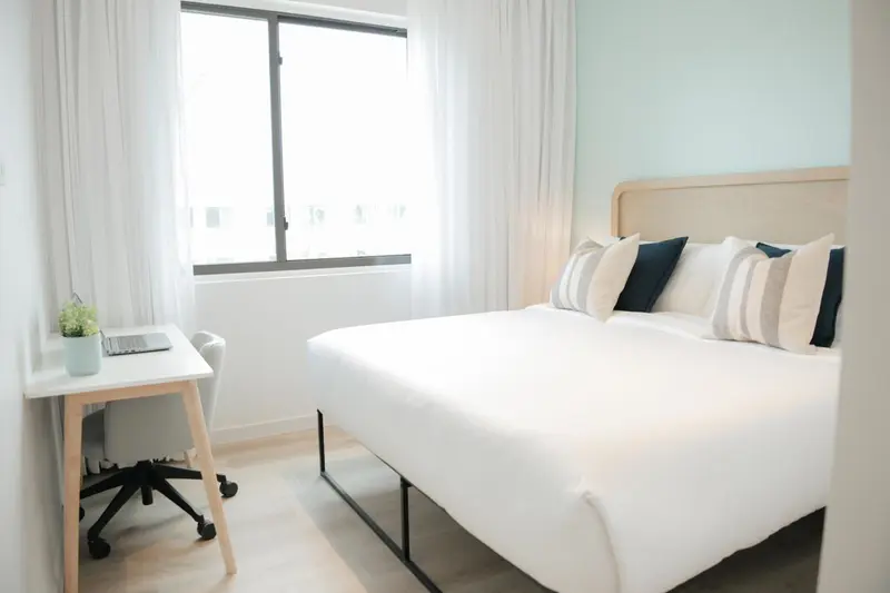 Une chambre lumineuse avec un lit double et un bureau.