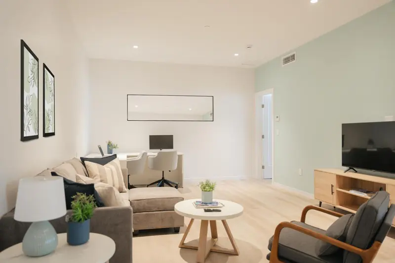 Espace de vie lumineux avec canapé, fauteuil et télévision.