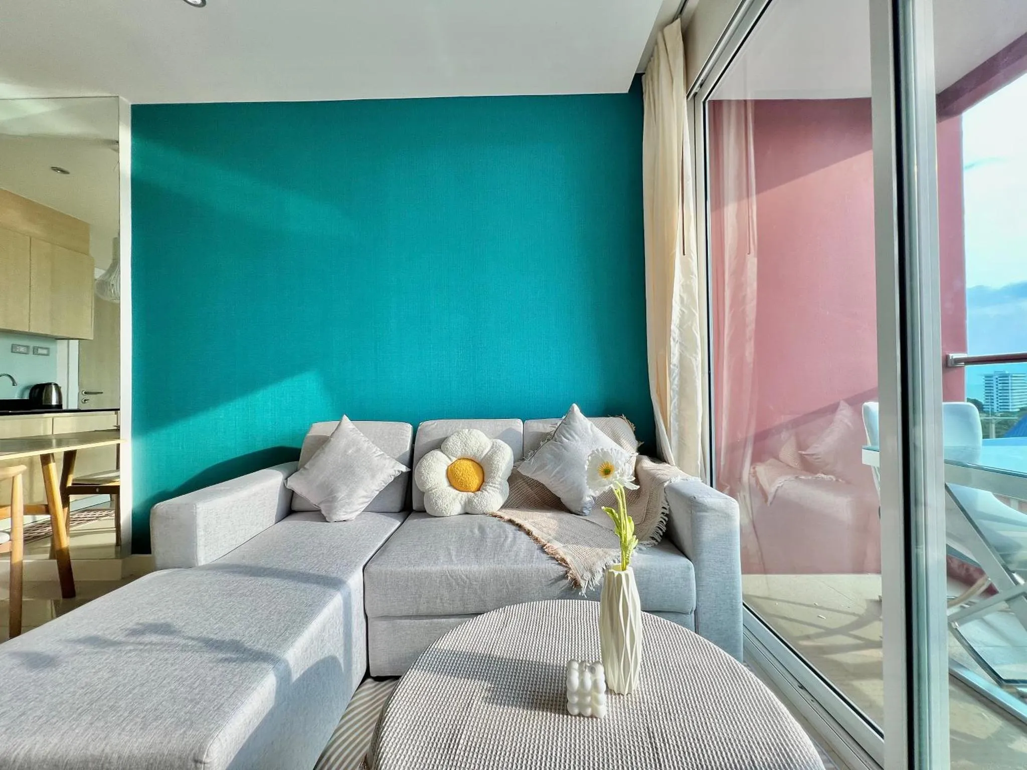Canapé gris et coussins dans un salon lumineux avec vue sur la mer.
