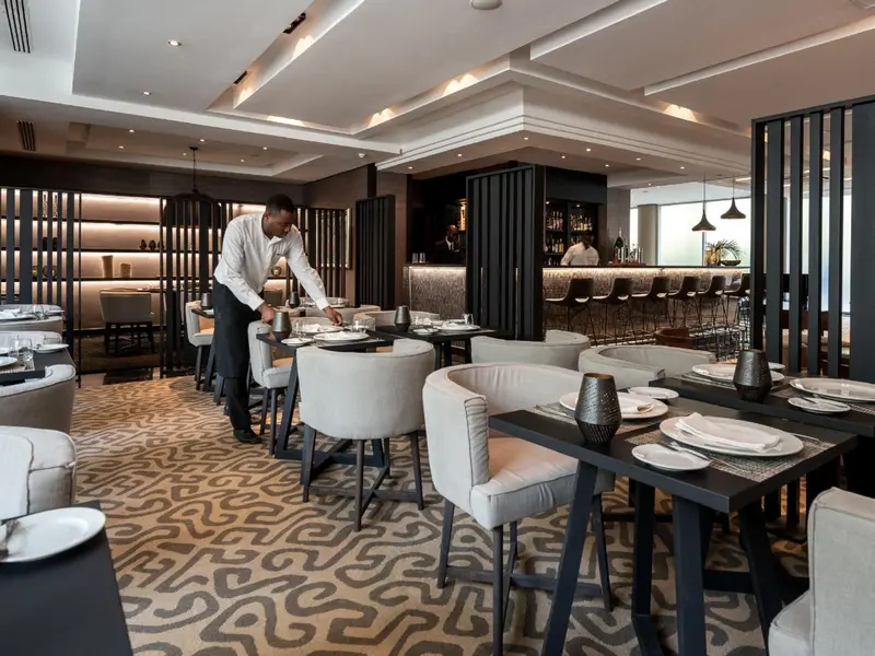 Une salle de restaurant lumineuse avec des tables dressées et du personnel en service.