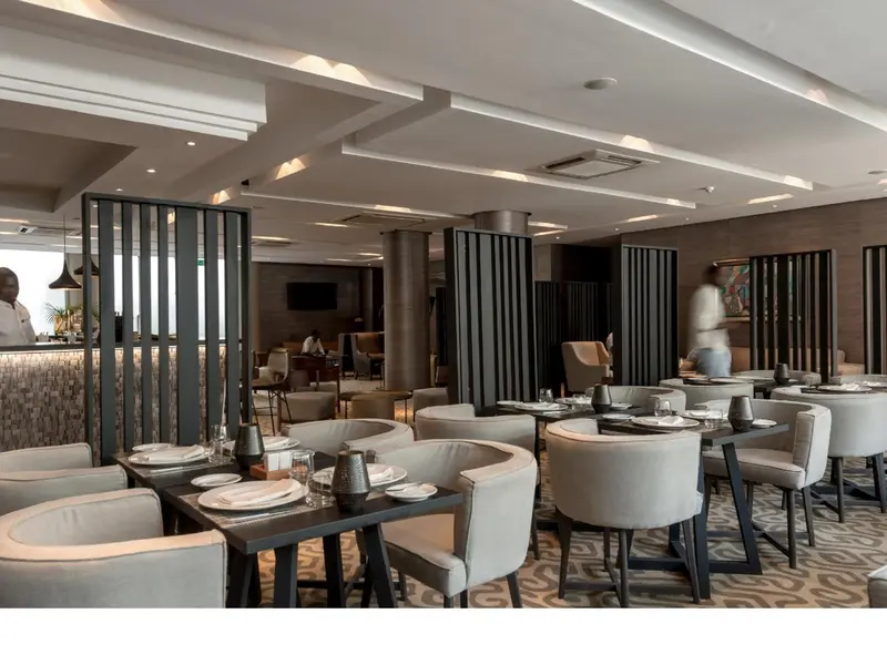 Une salle de restaurant moderne avec des tables dressées et un comptoir de bar.