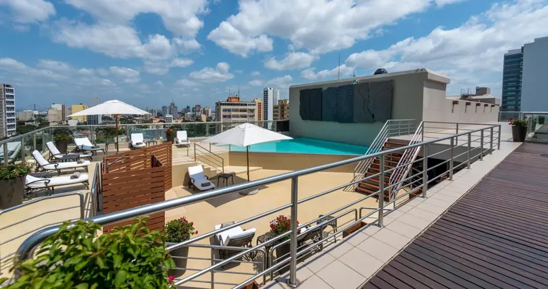 Terrasse aménagée avec transats et piscine sur le toit d'un bâtiment.