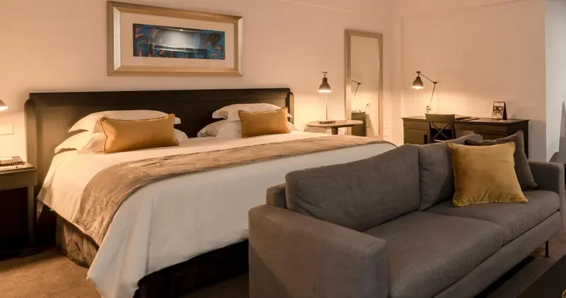 Une chambre lumineuse avec un grand lit et un coin salon.