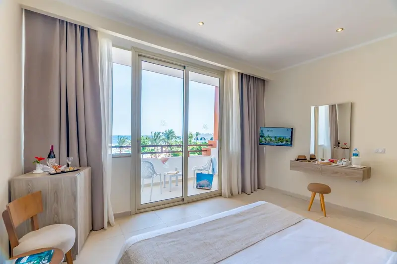Une chambre lumineuse avec un accès direct à un balcon offrant une vue sur la mer.