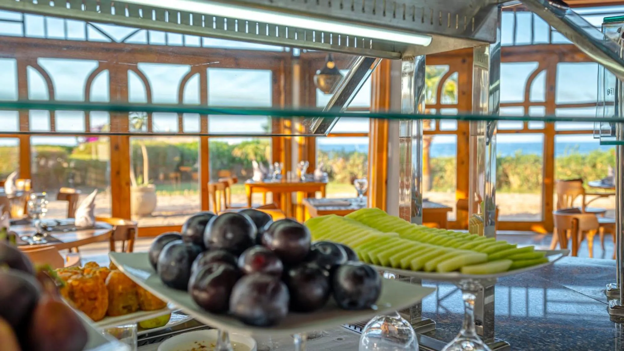 Un buffet de fruits frais est présenté dans un espace lumineux avec vue sur la mer.