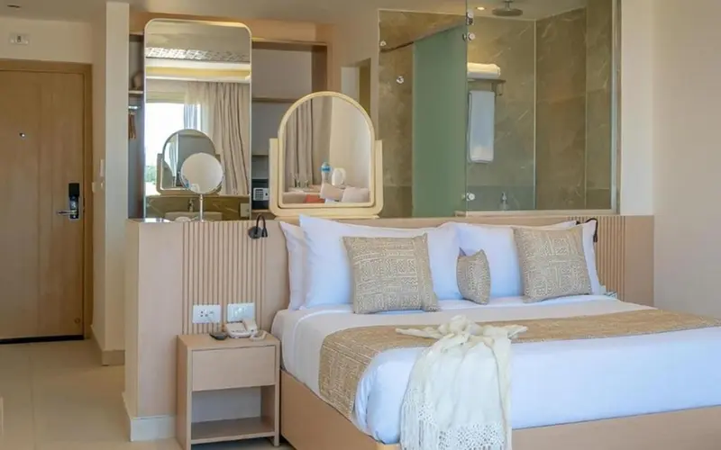 Une chambre lumineuse avec un grand lit et un espace coiffeuse.